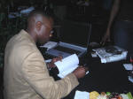 Maurice Skillern in action signing a book for a guest at Messages 2nd edition book release party